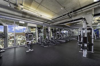 A spacious fitness center with cardio equipment and a view of the city